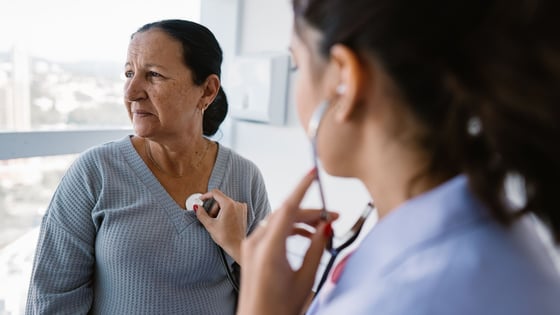 Nurse listening to patient's heartbeat through stethoscope