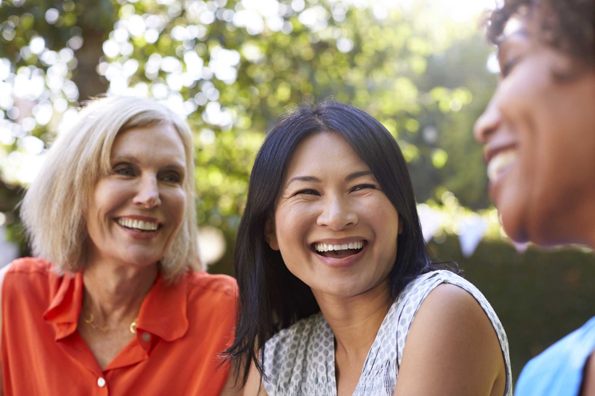 Three women enjoying each other's company, sharing laughter under the warm sun.