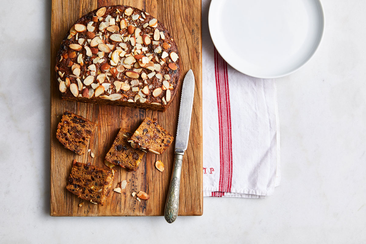 A cake with nuts on a cutting board, ready to be served