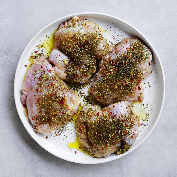 Chicken thigh fillets seasoned with dried herbs and olive oil