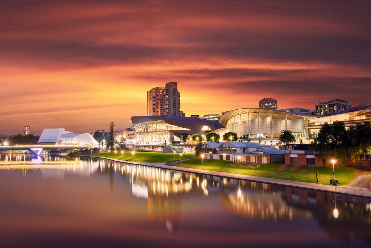 A picturesque city skyline at sunset, reflecting on a serene river, creating a captivating view.