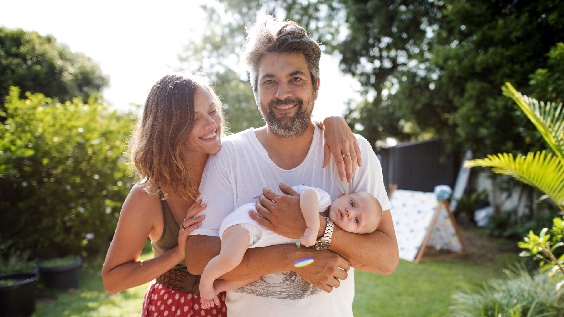 A young family standing in a backyard
