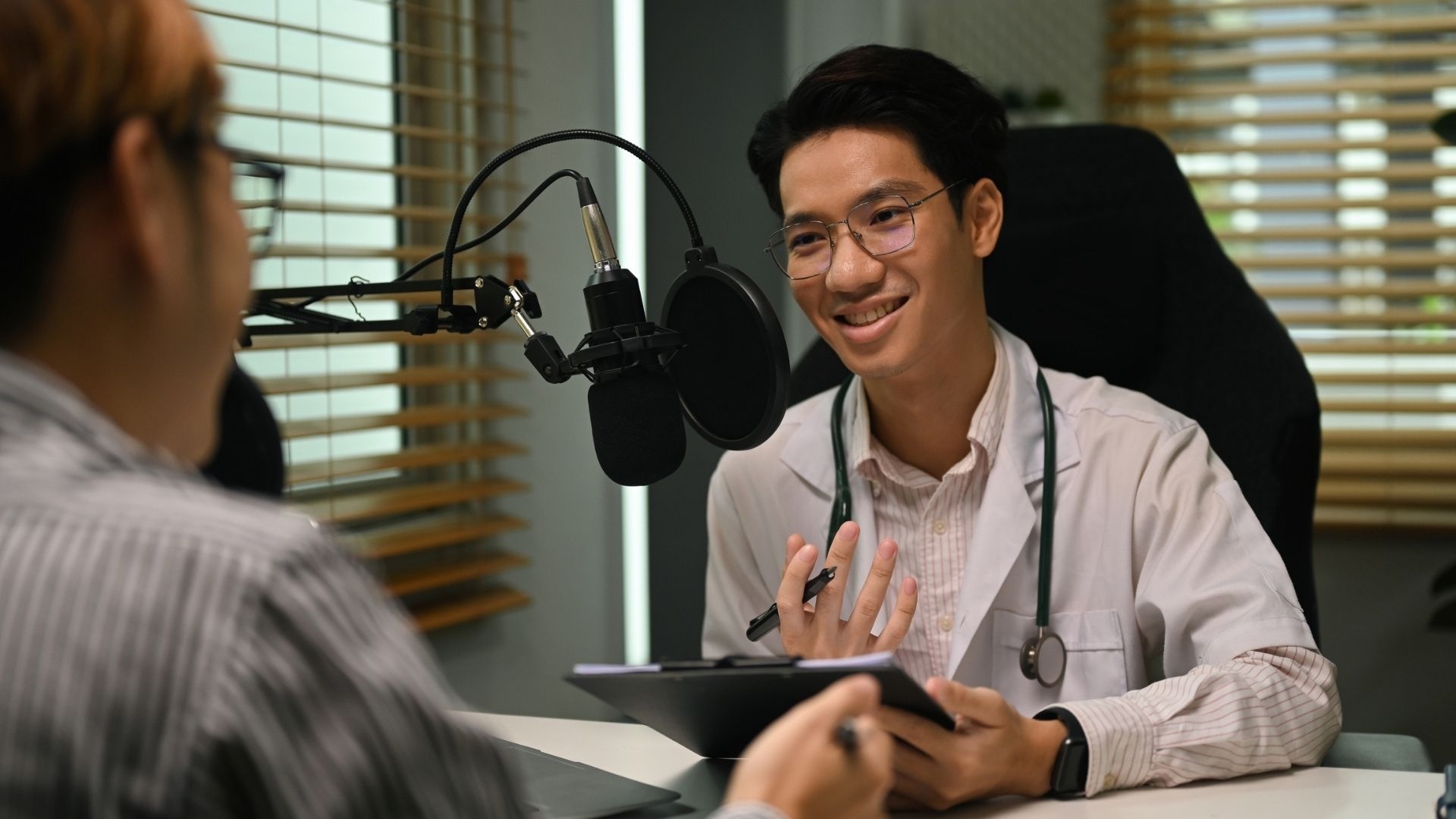 Friendly doctor in white coat and stethoscope making medication advise via online podcast, online medical blog from home.