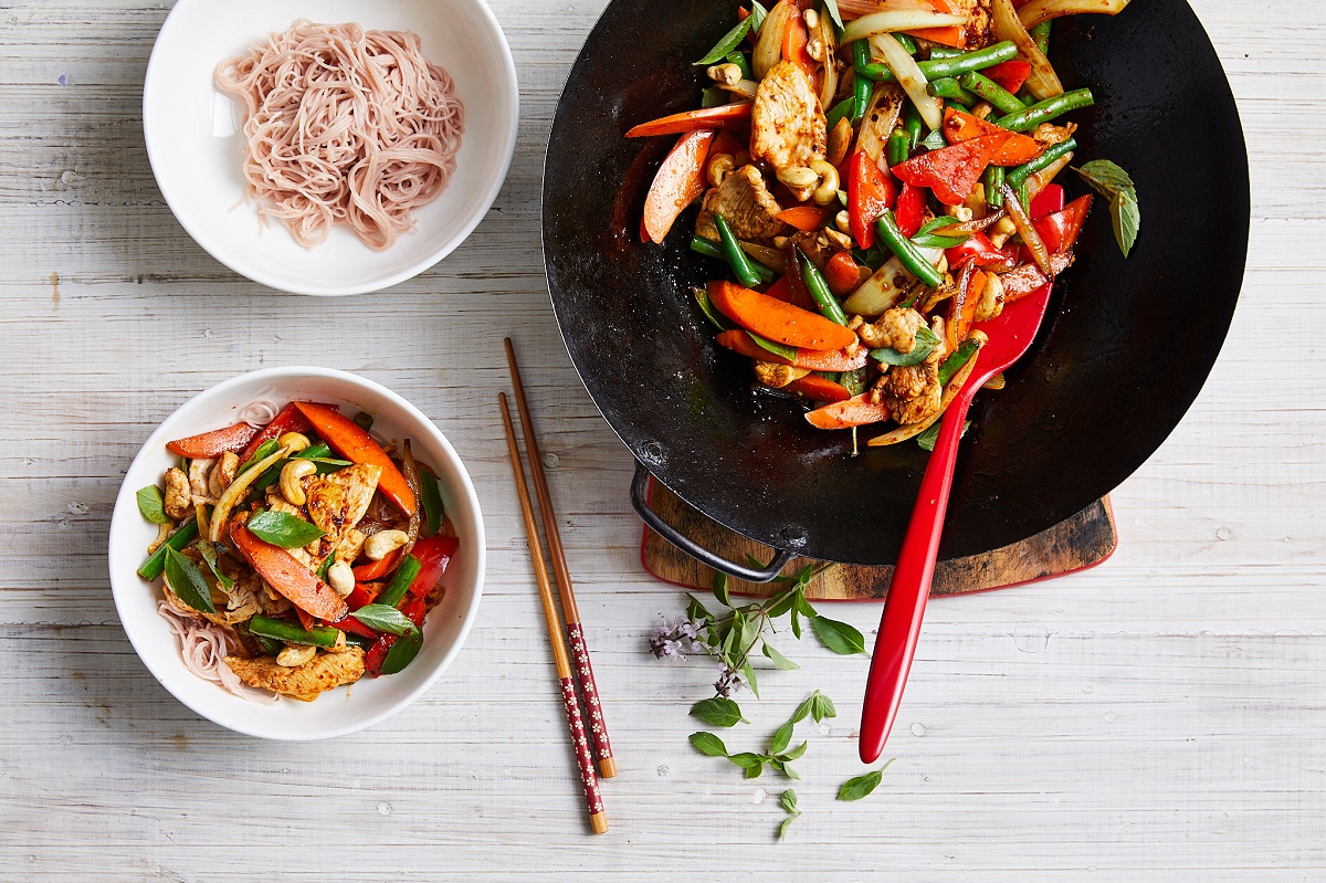  A colorful bowl of stir fry with mixed vegetables and a separate bowl of noodles on the side.