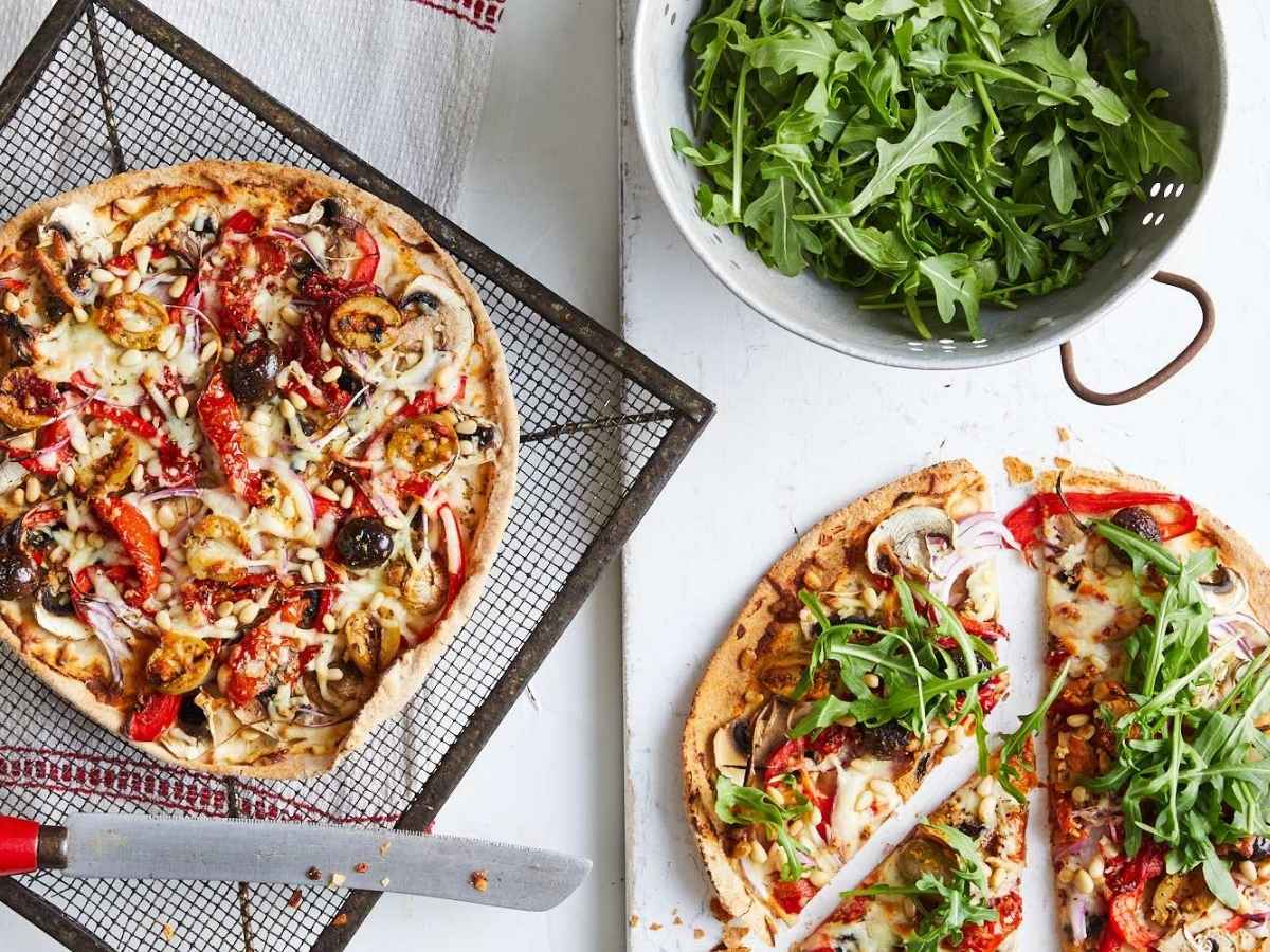 Mediterranean antipasto pizza served on a board with toppings