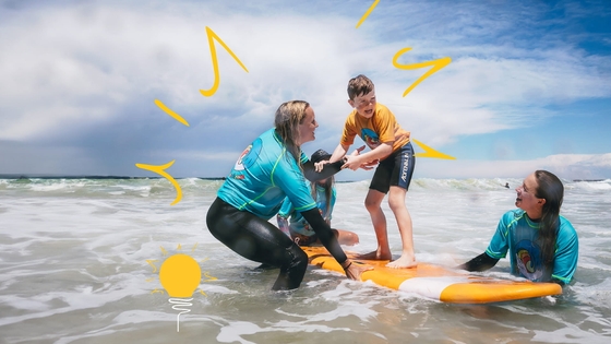 A woman and two children riding a surfboard in the ocean, enjoying a fun-filled day of surfing together.