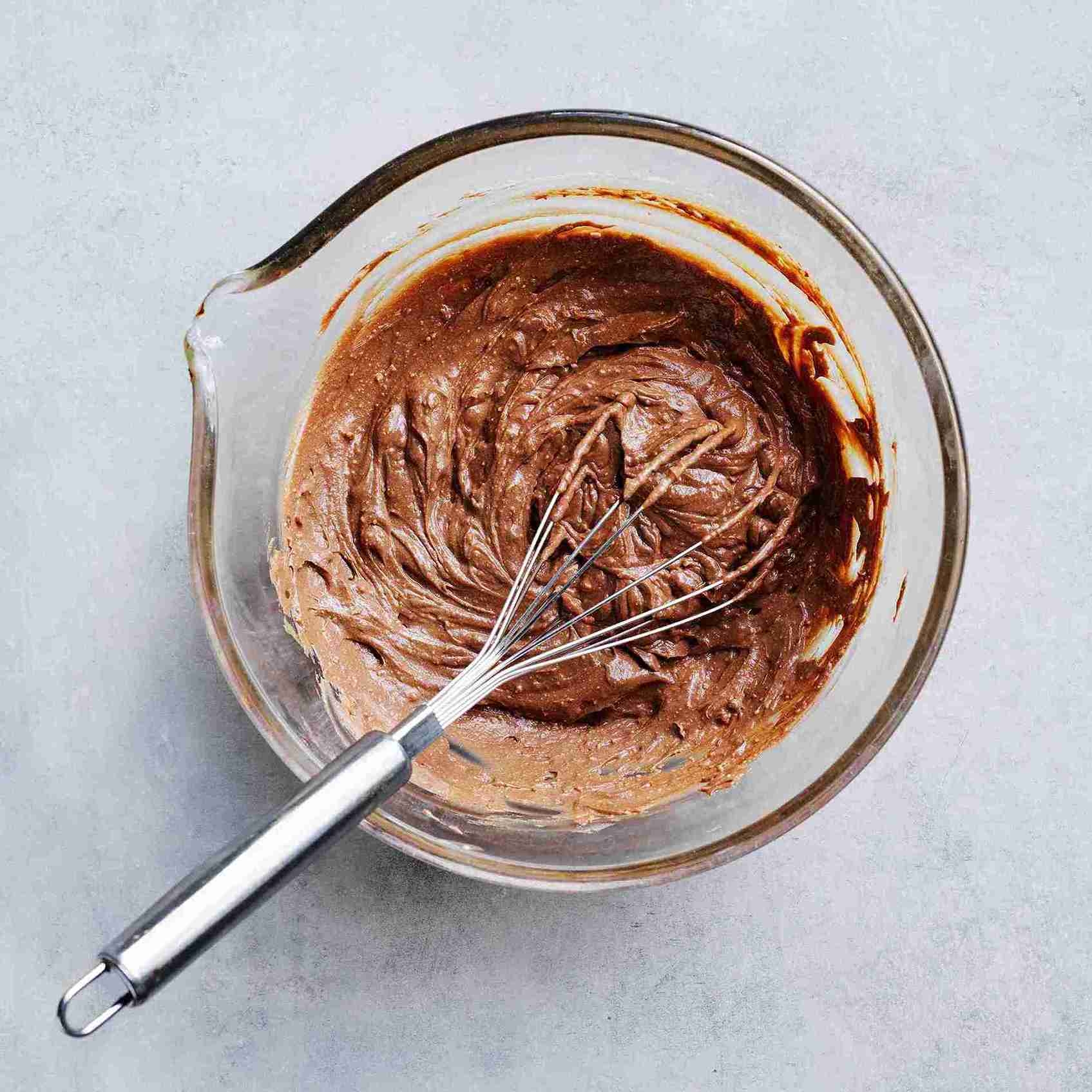 ricotta mixture being whisked with melted chocolate in a large bowl