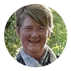 A smiling woman wearing glasses and a scarf.