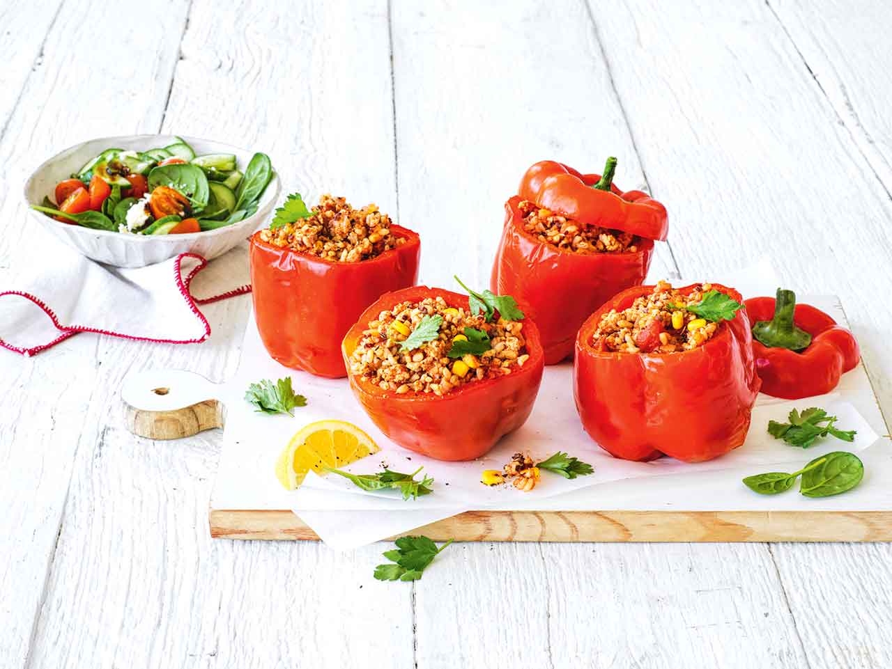 A plate with 2 stuffed peppers and a salad