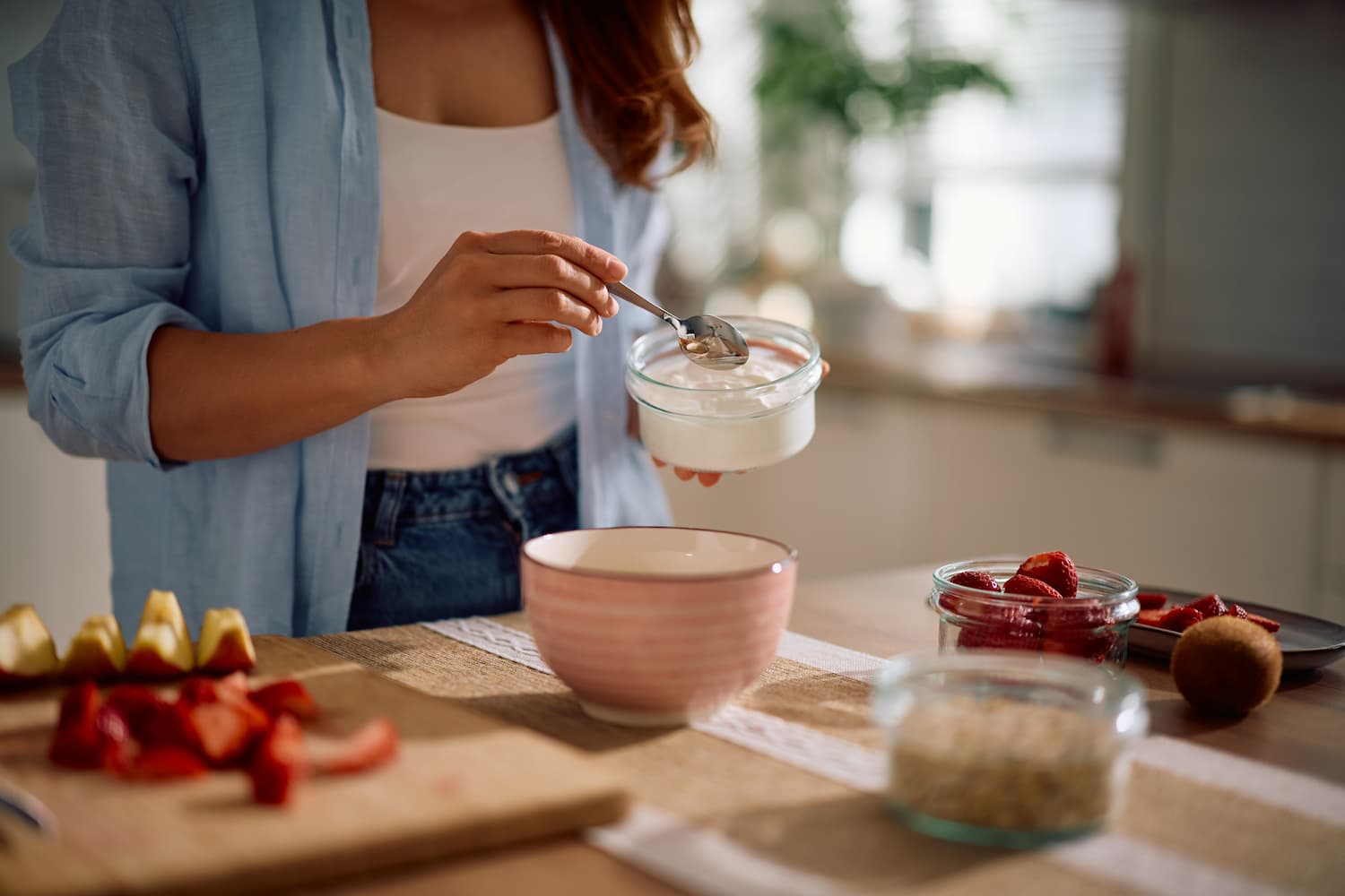 Close up of woman adding non fat yogurt while making healthy breakfast at home