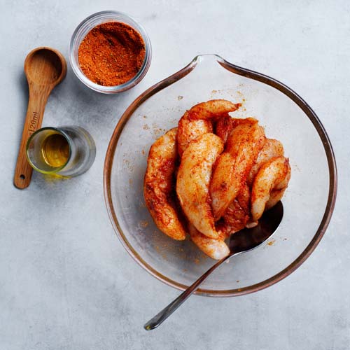 Tossing chicken in spice mix