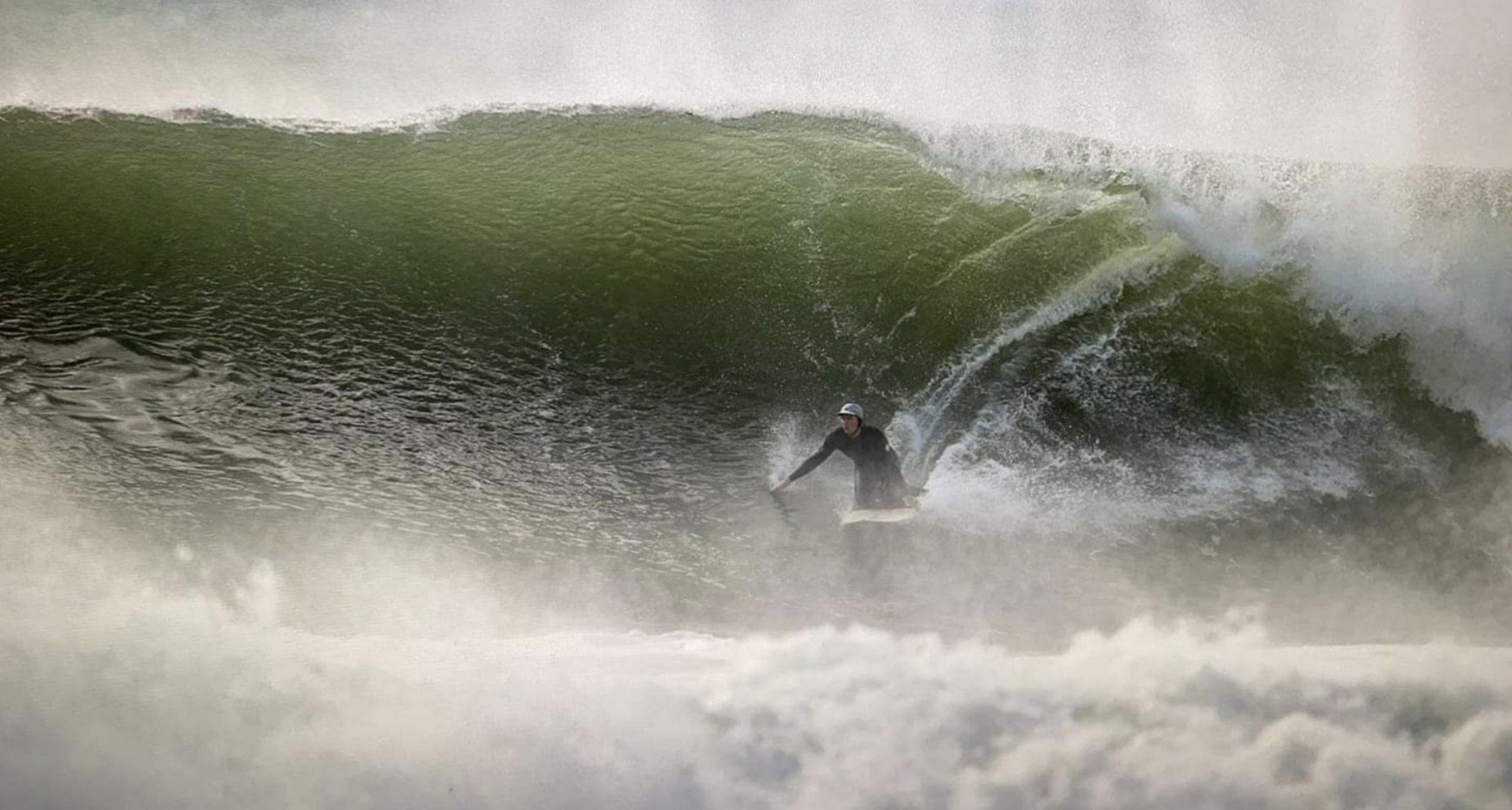 A surfer rides a large breaking wave, returning to the sport after recovering from a cardiac arrest.