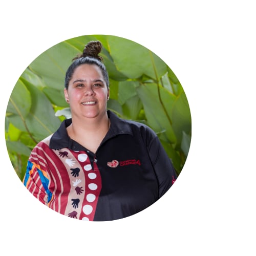 headshot of Woman standing in front of a leafy green background smiling 