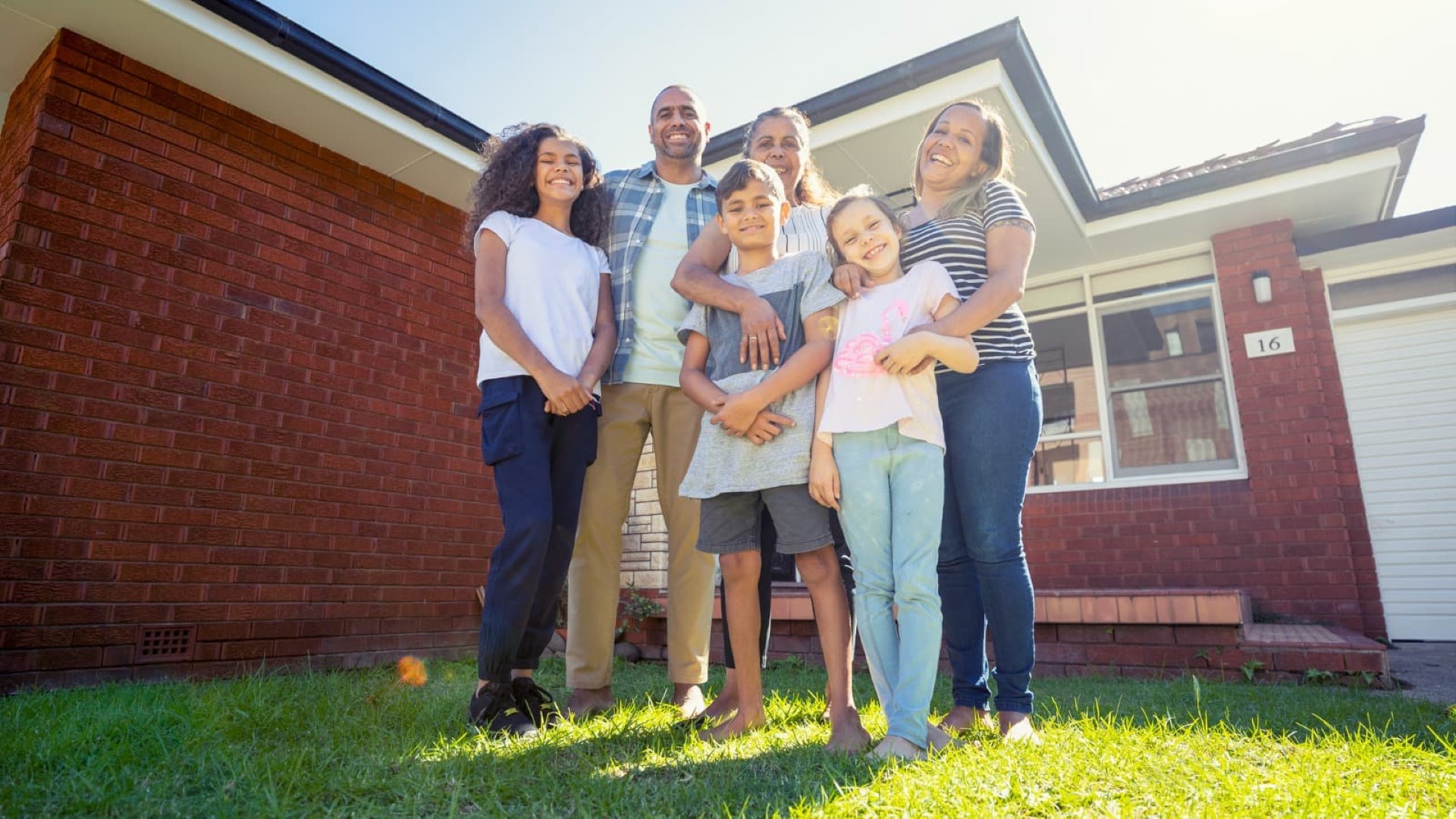 Family of six standing in front of house