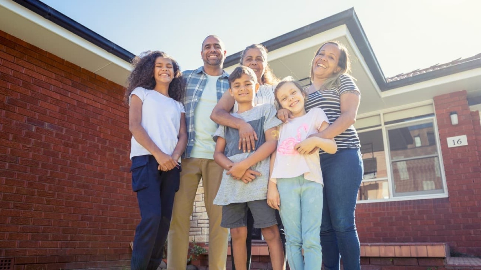 Family of six standing in front of house