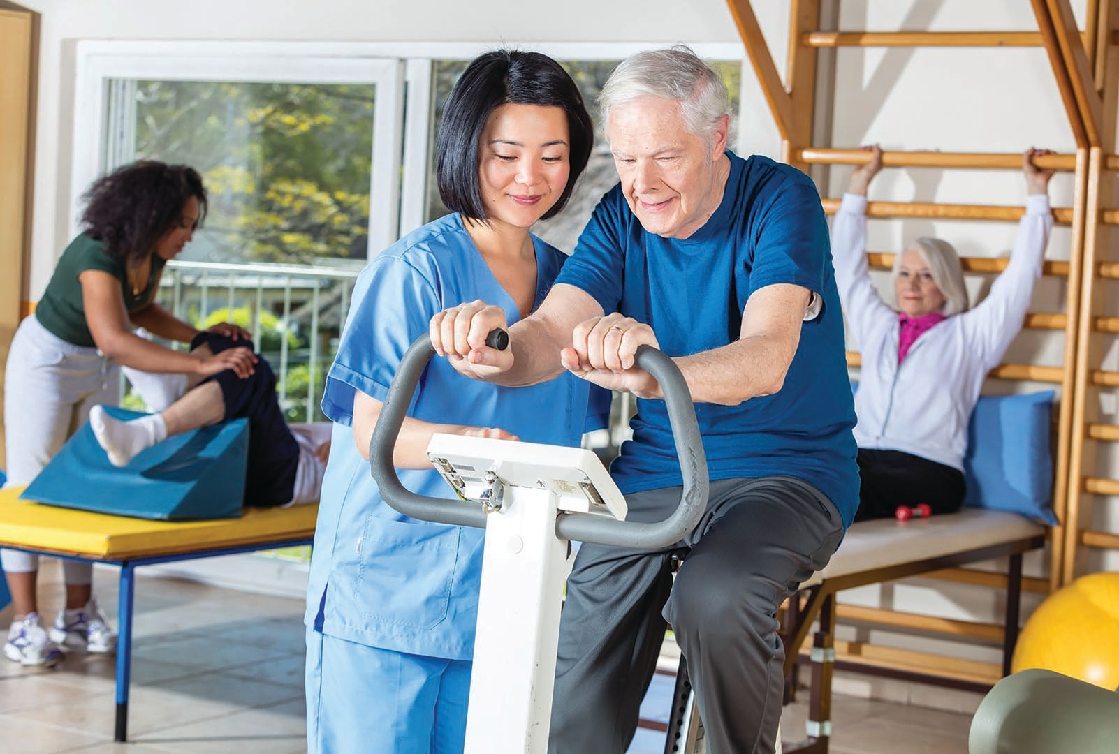 Cardiac rehab physio with an older patient on an exercise bike
