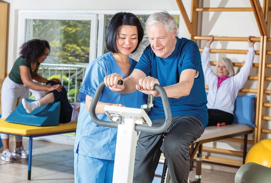 Cardiac rehab physio with an older patient on an exercise bike