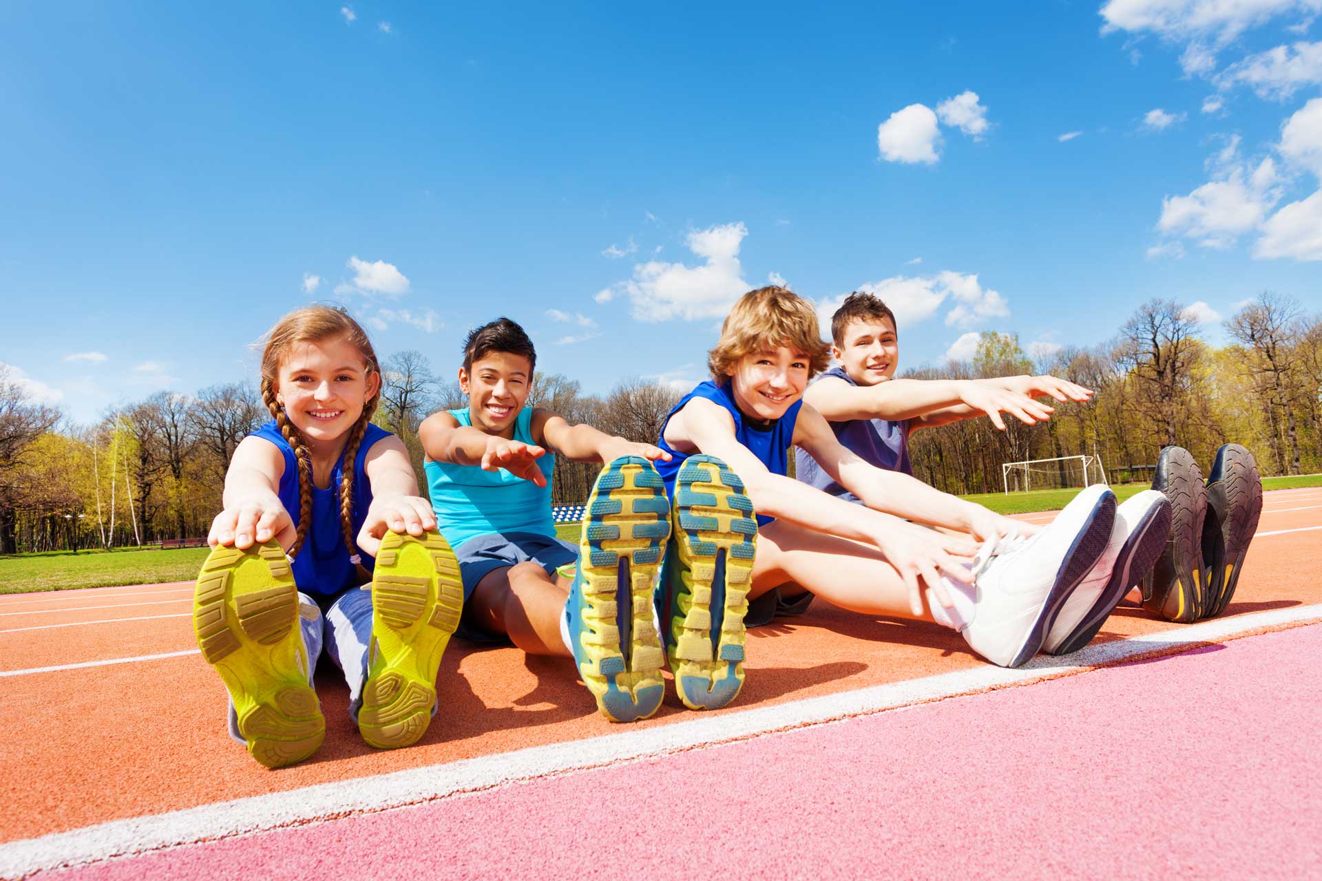 Kids stretching on a running track on a sunny day
