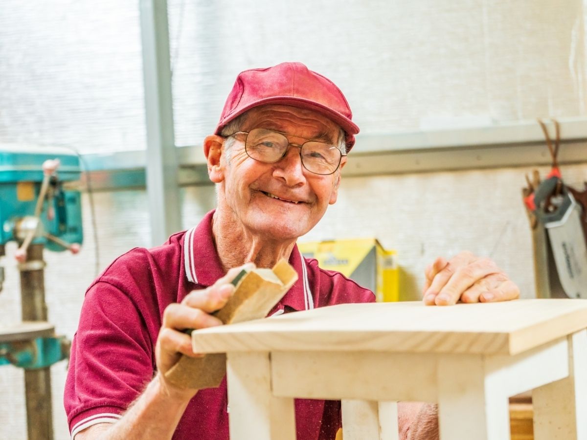 Older man at a workshop smiling at the camera