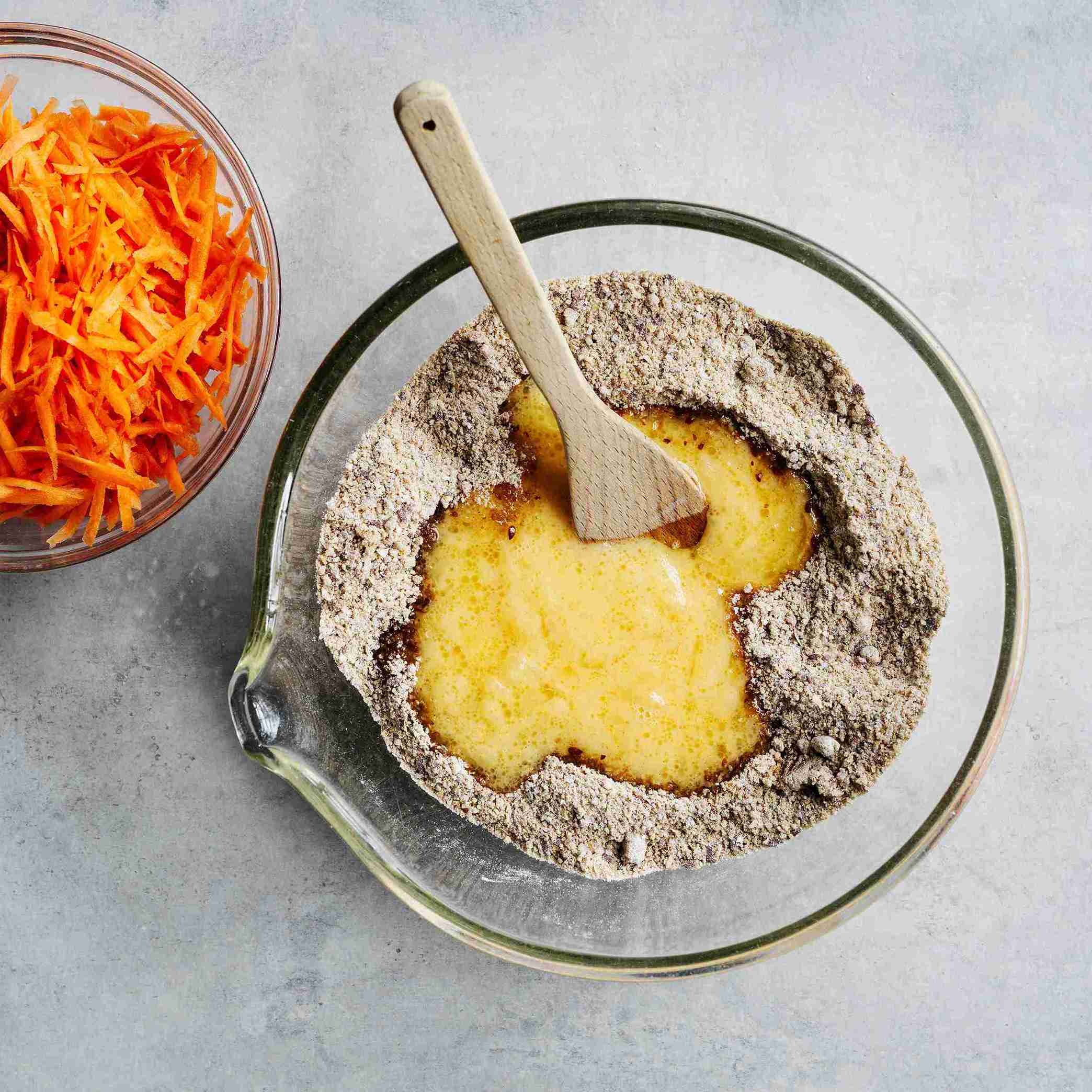 whisking and pouring eggs, apple puree and oil into the flour mixture