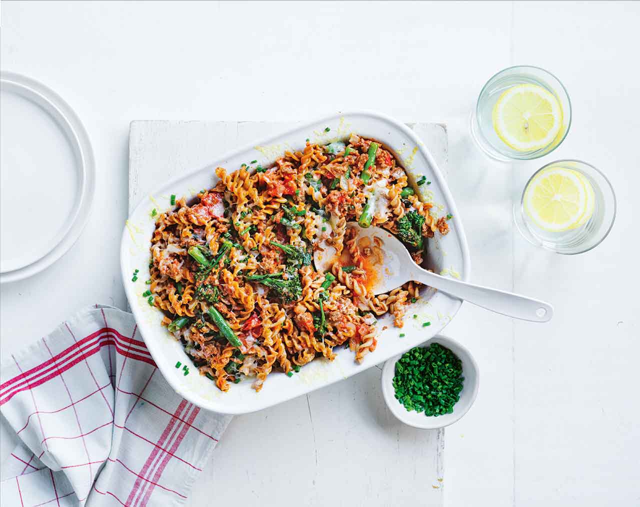 Beef and green veggie pasta bake on a table with 2 glasses
