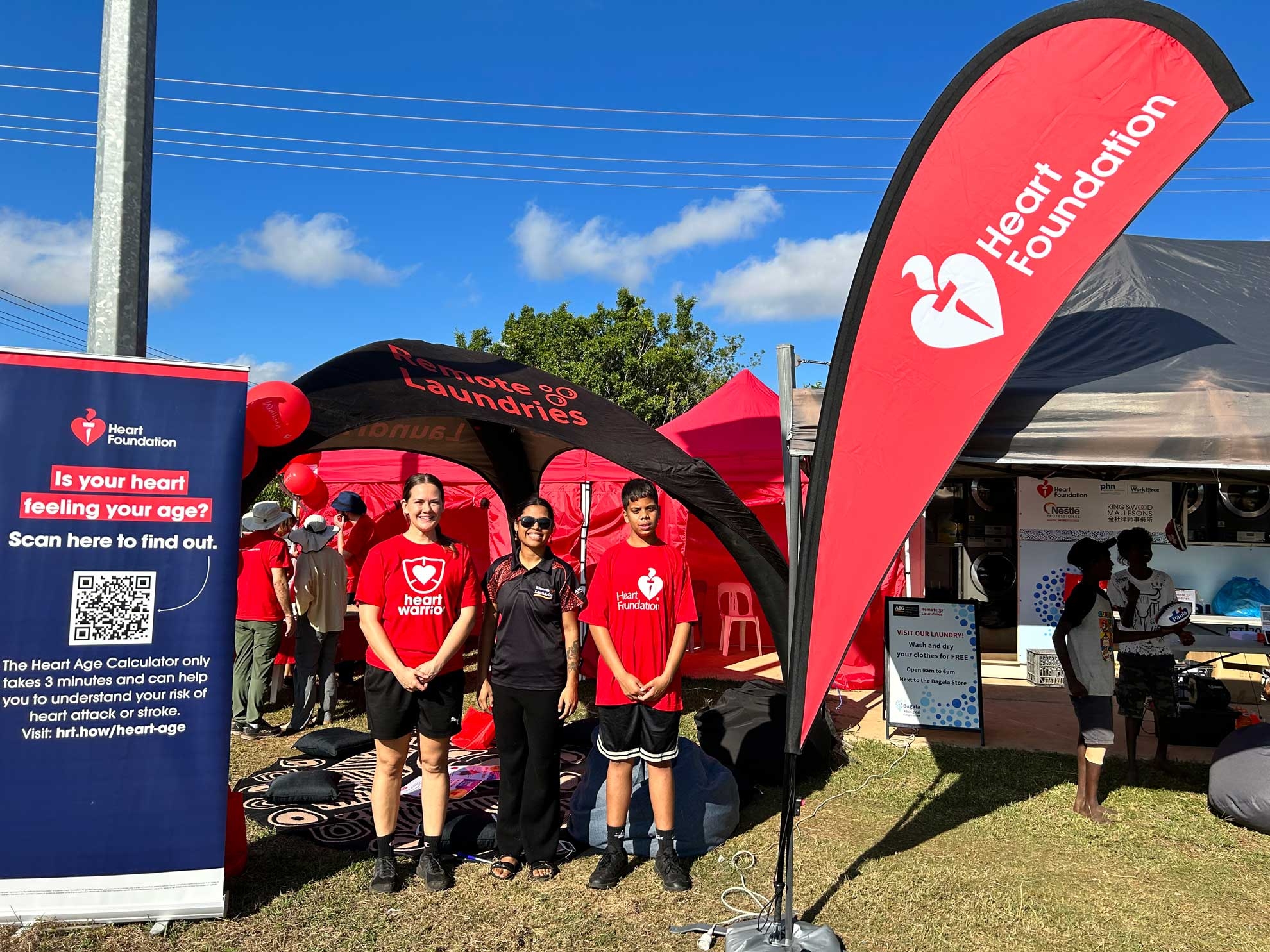 Team in red Heart Foundation tshirts in front of Remote Laundries project tent at Barunga Festival 2023
