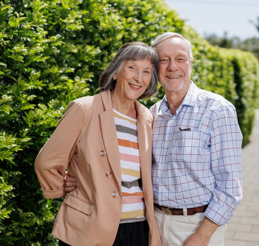 Janet and Patrick standing in front of a hedge