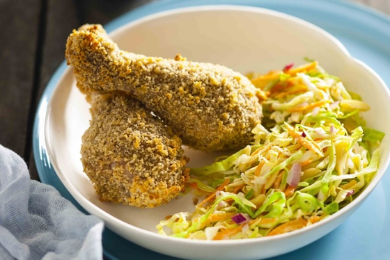 A plate showcasing golden fried chicken accompanied by a side of refreshing coleslaw