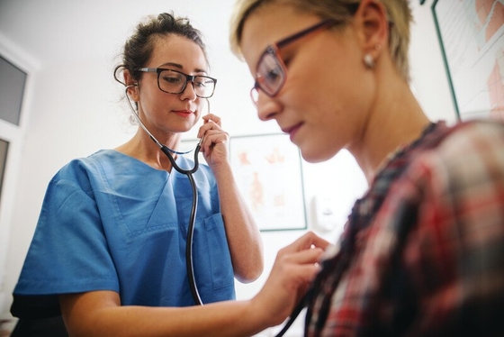 A female doctor carefully examines a patient's chest, using a stethoscope to listen for any abnormalities.