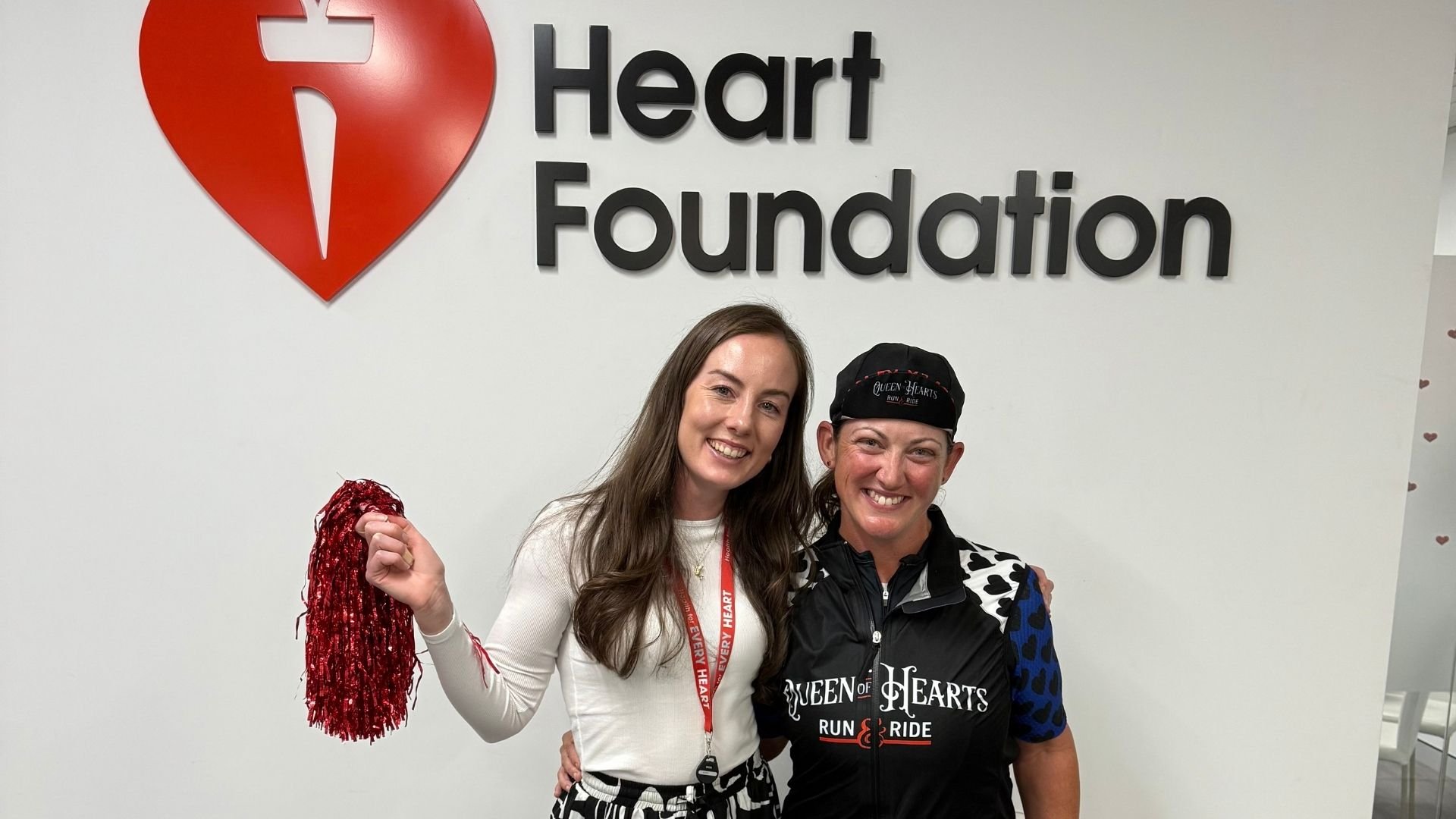 Alicia Brown standing with community fundraiser Dawn Beaumont in front of the Heart Foundation sign