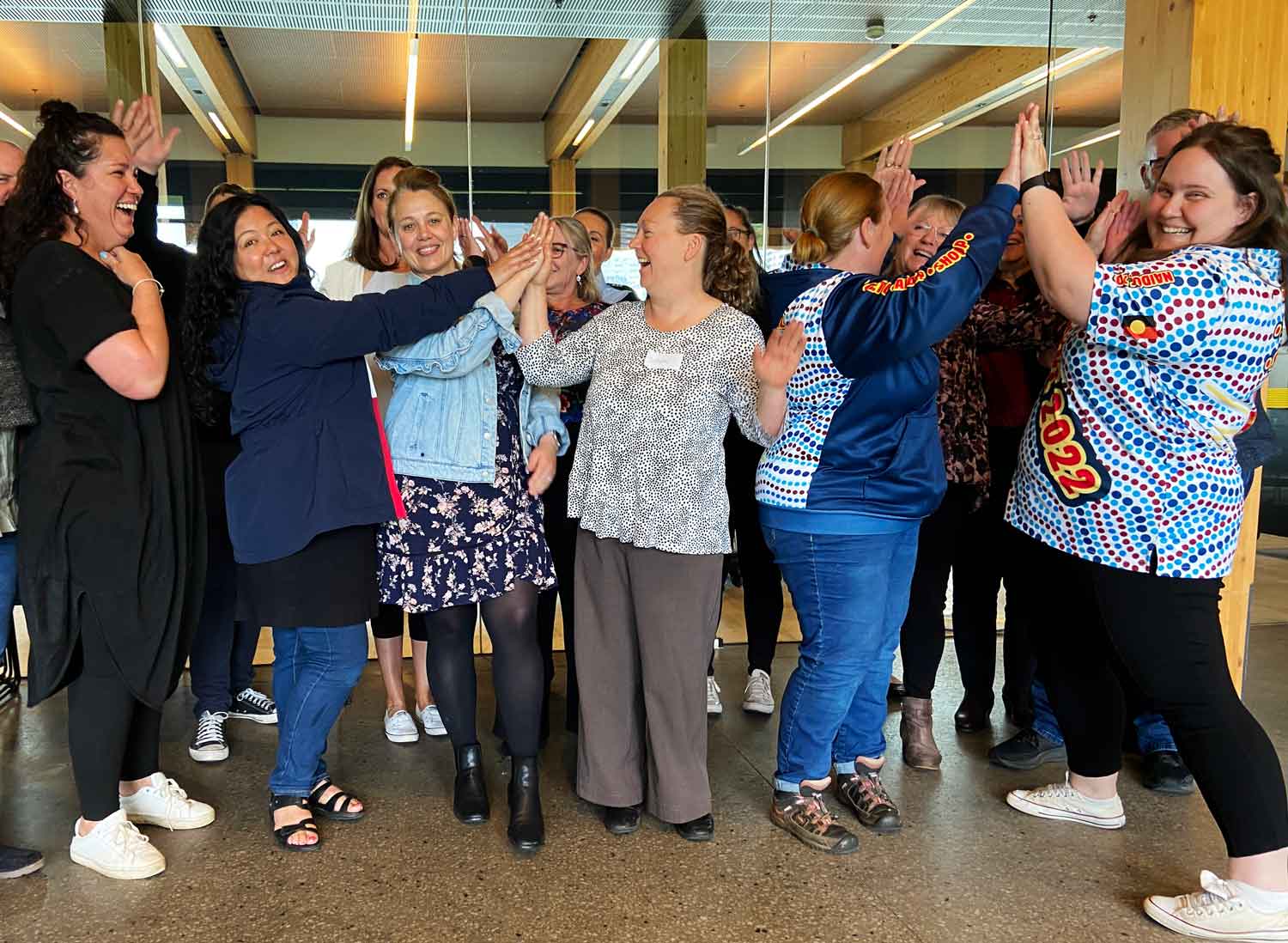 Group of women in a workplace setting, congratulating and high fiving each other