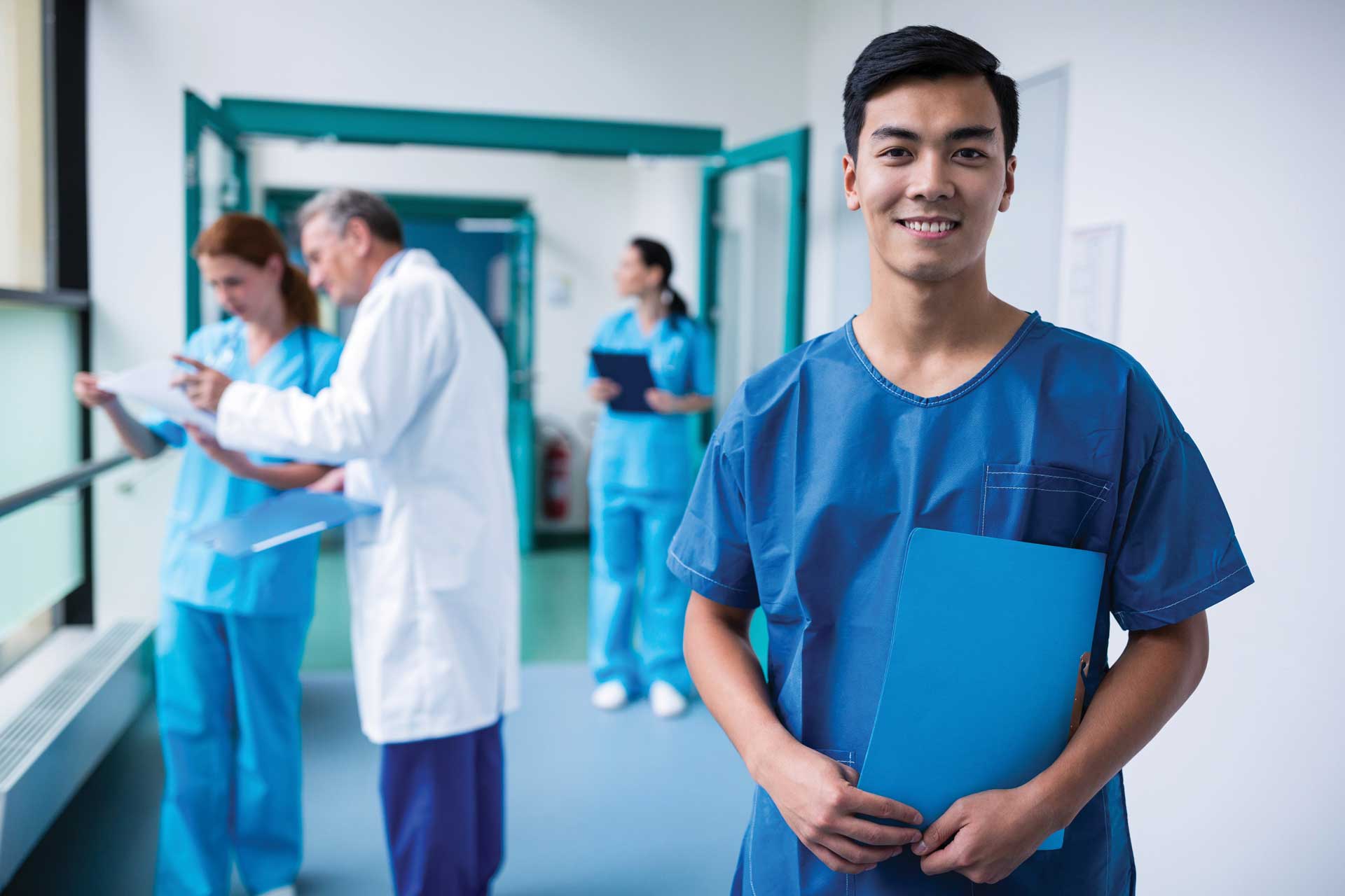 Smiling male healthcare professional in scrubs standing in a hospital environment