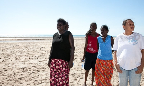 A group of women standing on the beach, enjoying the sun and the ocean waves.