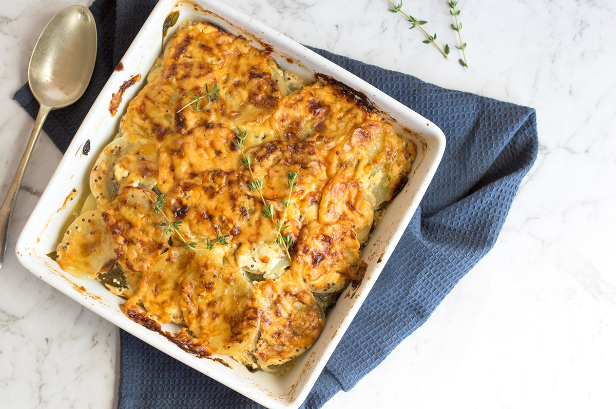 Delicious baked potato casserole in a white dish, served with a spoon
