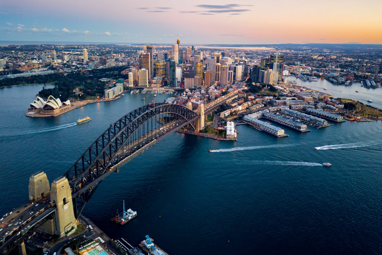 A breathtaking aerial view of Sydney's skyline at sunset, showcasing the iconic Sydney Harbour Bridge and the city's stunning cityscape.