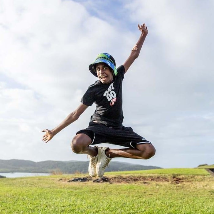 Child jumping in the air outdoors on a grassy open space