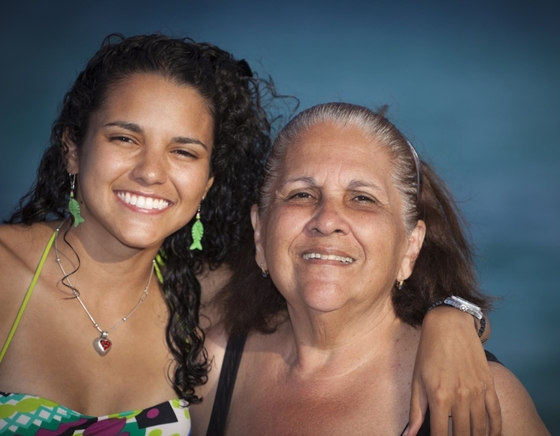 A woman and her mother smiling while posing for a photo, capturing a heartwarming moment between generations.