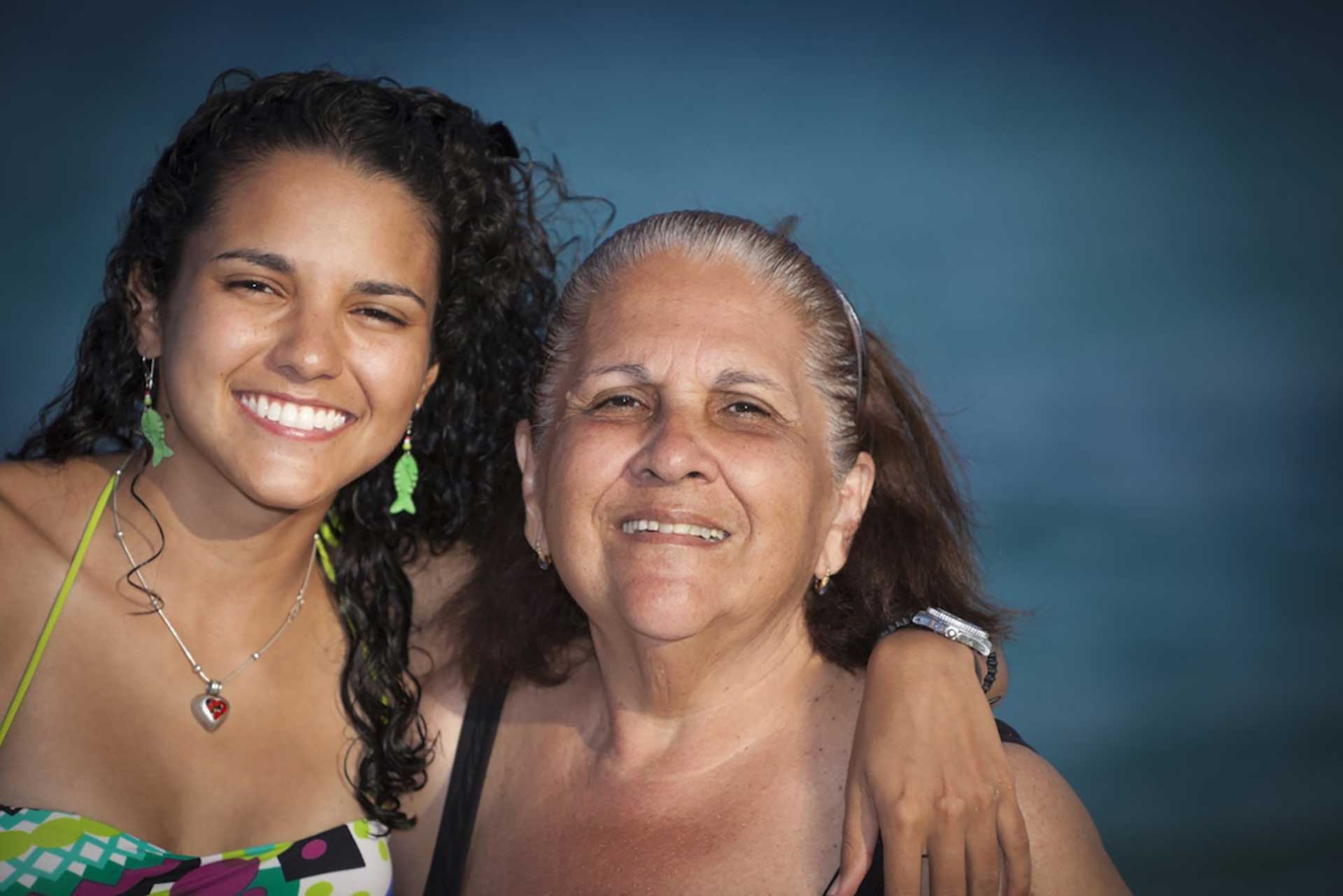 A woman and her mother smiling while posing for a photo, capturing a heartwarming moment between generations.