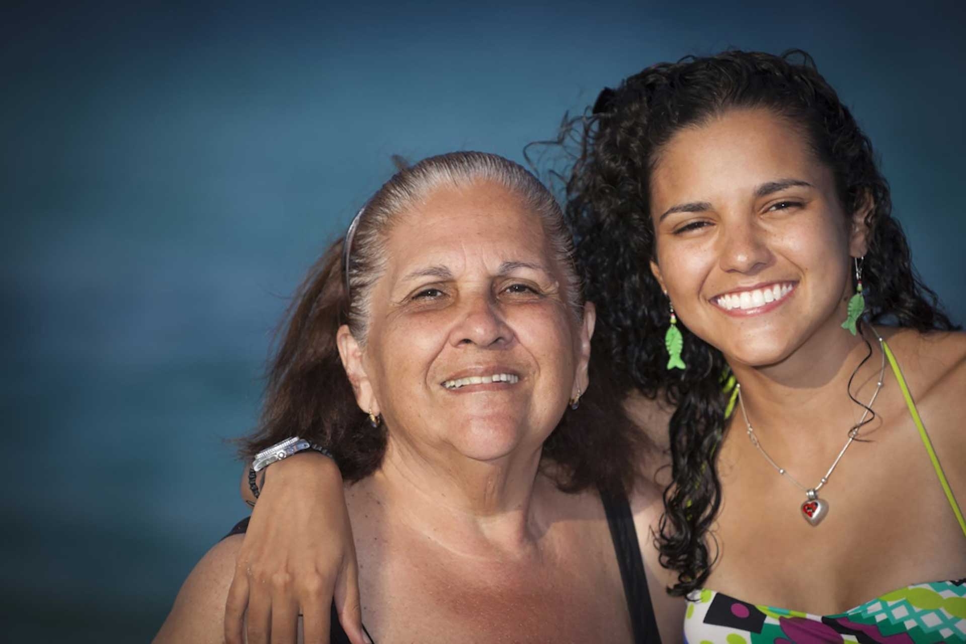 A woman and her mother smiling while posing for a photo, capturing a heartwarming moment between generations.