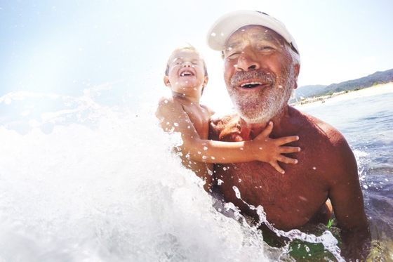 An older man and a young boy joyfully playing in the ocean, creating lasting memories together.