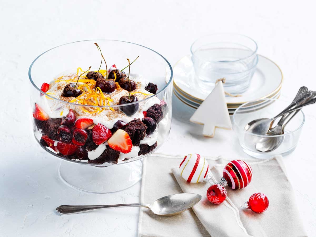 Chocolate and berry trifle with cherries and cream in a glass bowl, festive holiday table setting