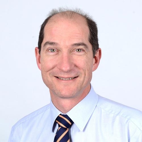 Anthony Russell in a blue shirt and tie, beaming with a warm smile.