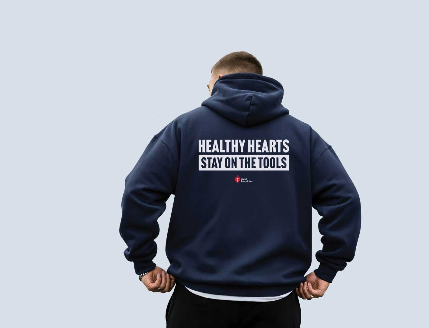 A man in a dark blue hoodie which says "Healthy hearts stay on the tools"