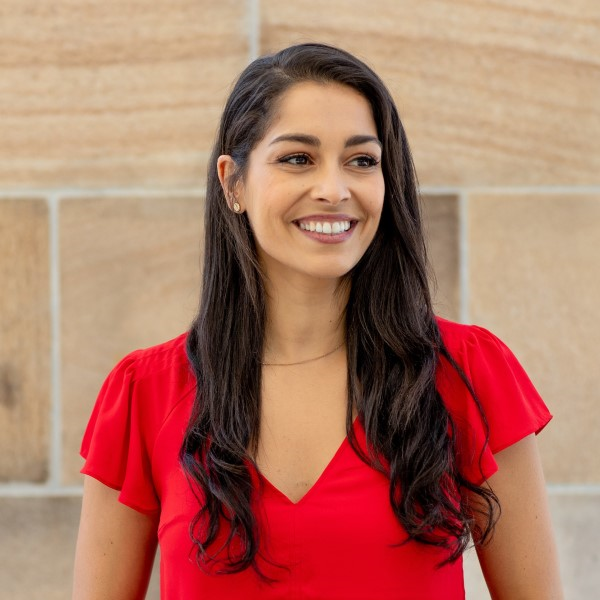 Gina Cleo in a red shirt smiling, radiating joy and happiness.