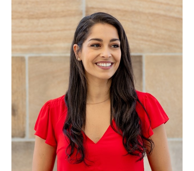 Gina Cleo in a red shirt smiling, radiating joy and happiness.