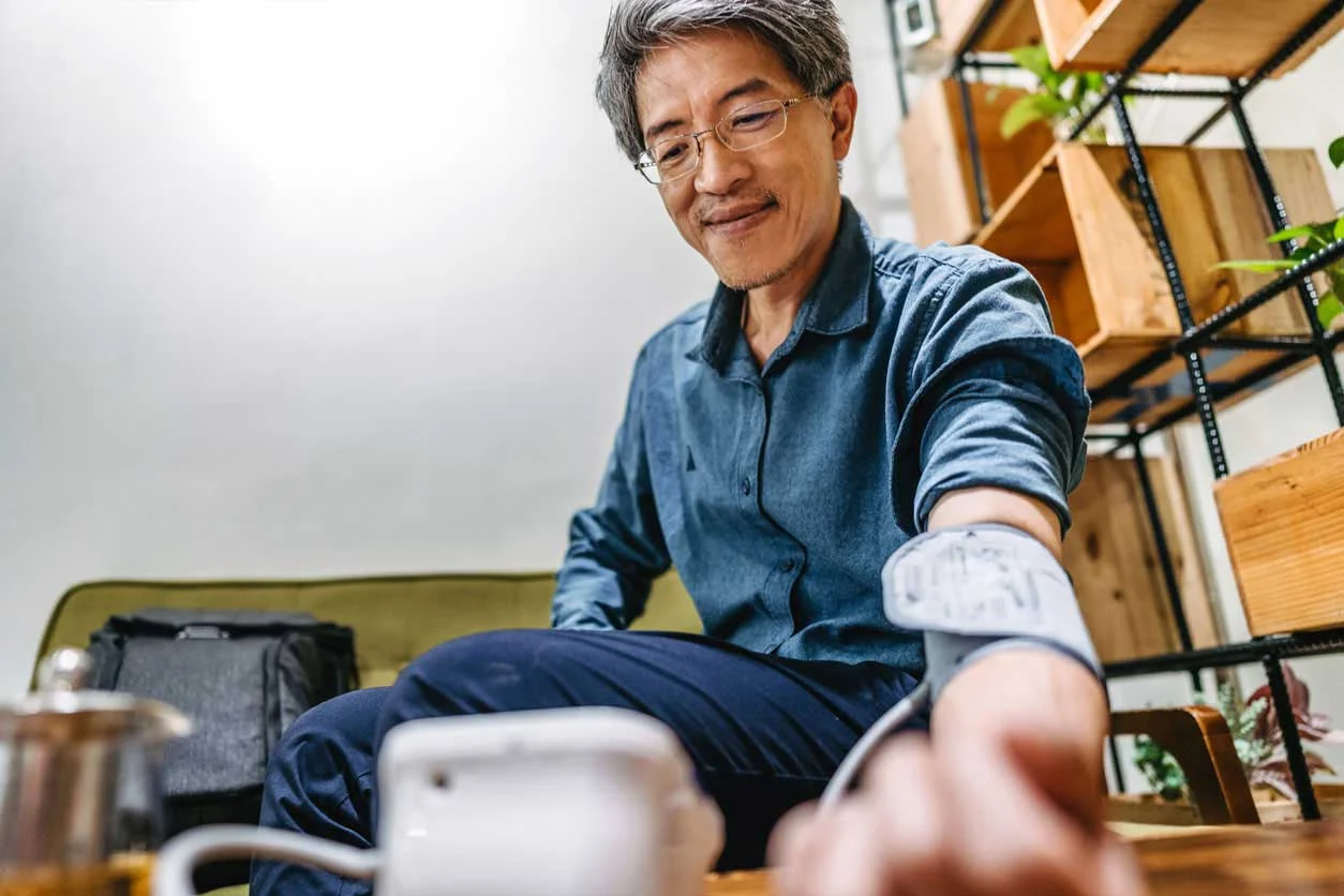 Man wearing glasses administering himself a blood pressure test