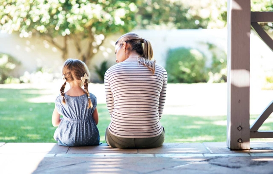 Young mother and daughter sitting together on step