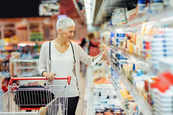 A woman browsing through the aisles of a grocery store, carefully selecting items for her shopping cart.