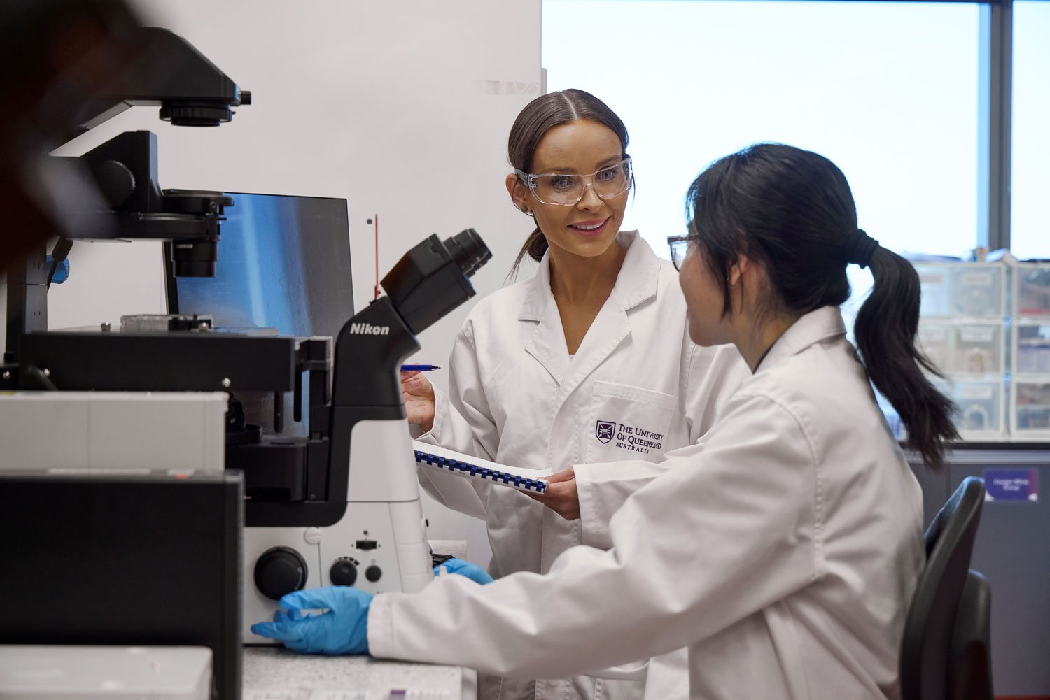 Two researchers working together at a microscope in a laboratory.