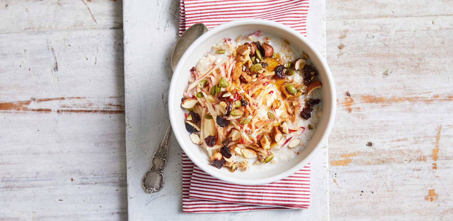 A bowl of oatmeal topped with nuts and raisins